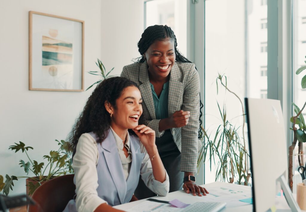 Teamwork, business people and women with computer, funny and help with conversation, publishing and joke. Employees, laughing or mentor in workplace, online humor or female empowerment with email